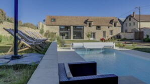 Ein modernes Haus mit Swimmingpool, Steinmauern und einem gepflegten Rasen.