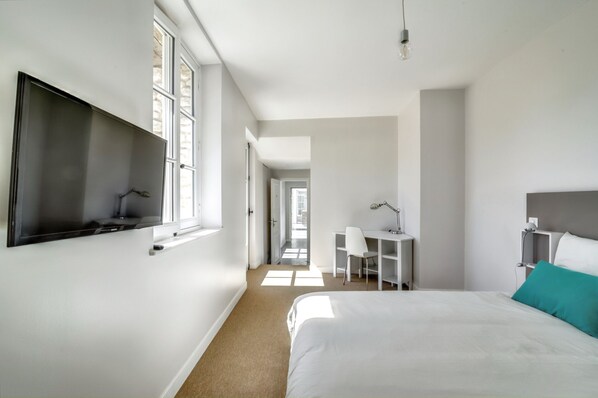 A modern hotel room with a large bed, a desk, and a TV mounted on the wall. - Homerez - Villa with Pool and Garden in Amponville (Amponville)