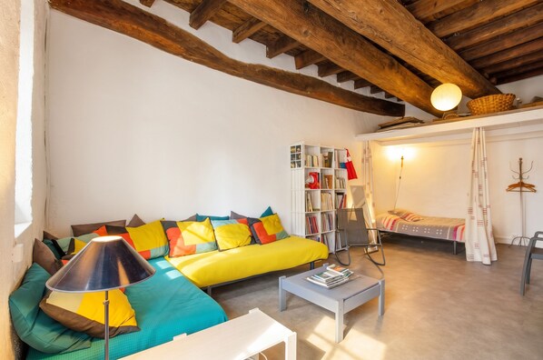 A cozy living room with a yellow sofa, a white coffee table, and a bookshelf.