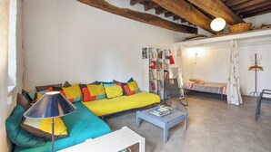A cozy living room with a yellow sofa, a white coffee table, and a bookshelf. - Homerez - Charming Studio in Villeneuve, 45m², balcony (Villeneuve-lès-Avignon)