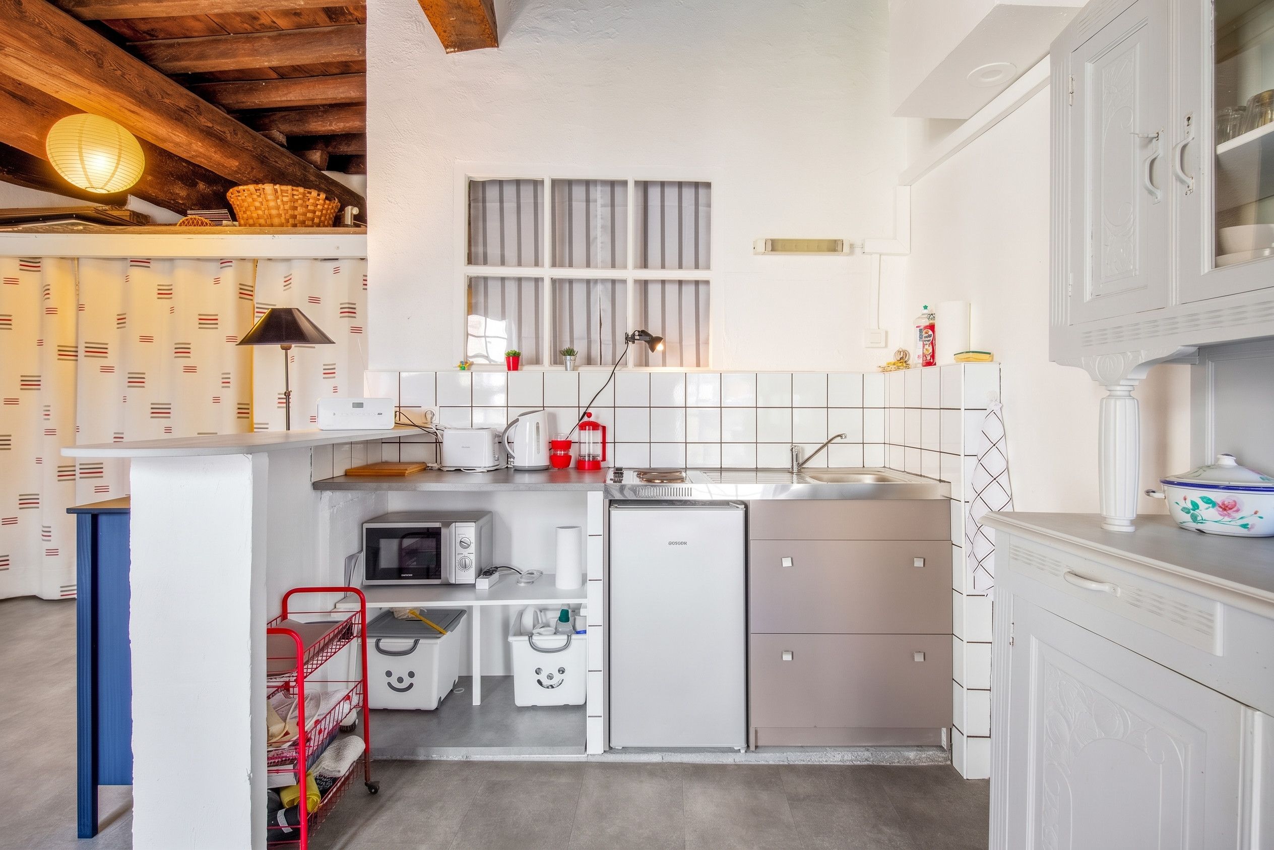 A compact kitchen with white cabinets, a microwave, a coffee maker, and a sink.