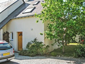 A building with a sloped roof, a wooden door, and a gravel driveway.