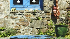 Un bâtiment en pierre avec une fenêtre bleue et un ornement suspendu composé de perles.