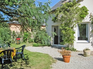 A patio with a table and chairs, surrounded by a gravel path and greenery.