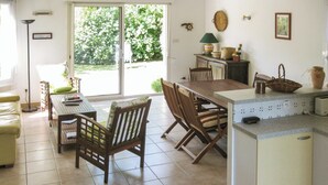 Une cuisine avec un coin repas, un petit îlot central et une vue sur la verdure à l’extérieur.