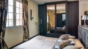 A bedroom with a bed, a mirror, a dresser, and a sliding door leading to a bathroom. - Exceptional Master House  et  Mooring (PORT GRIMAUD)