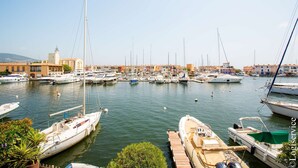 A marina with various boats docked, a clear sky, and buildings in the background. - Exceptional Master House  et  Mooring (PORT GRIMAUD)