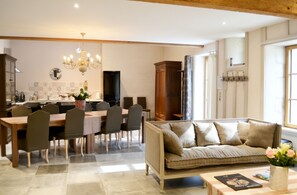 A modern kitchen with a dining area, a sofa, and a window with curtains. - Homerez - Spacious House in Cabariot, 180m², Garden (Cabariot)