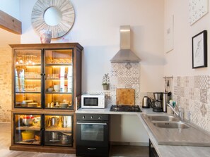 A modern kitchen with a built-in oven, microwave, and stainless steel sink. - Homerez - Spacious House in Cabariot, 180m², Garden (Cabariot)
