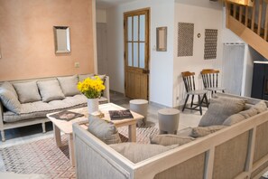 A living room with a sofa, coffee table, and a dining area with chairs. - Homerez - Spacious House in Cabariot, 180m², Garden (Cabariot)