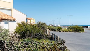 Un edificio costiero con tetto in tegole, circondato da vegetazione e un cielo azzurro limpido.