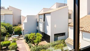 Zona residenziale caratterizzata da edifici bianchi, un piccolo giardino recintato e cielo sereno.