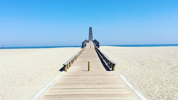 A wooden boardwalk leading to a pier with a lattice structure at the end, on a sandy beach. - Cozy 2-Bedroom Villa + Mezzanine, Sleeps 6, Steps to Beach, Parking, TV, Washer (Port Leucate)