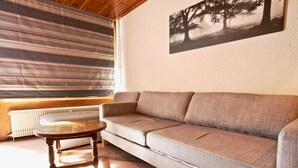 A living room with a sofa, a round wooden table, and a radiator.