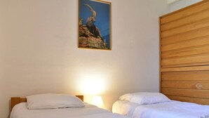 A hotel room with two beds, a wooden headboard, and a framed picture on the wall.