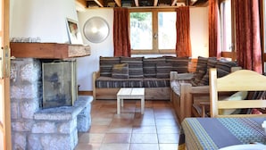 A cozy living room with a stone fireplace, a sofa, a small table, and a wooden bench.