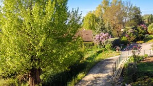 A rural pathway leading to a traditional house surrounded by lush greenery and flowering plants. - Homerez - House in Gap (Gap)