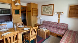 A compact living space with a kitchenette, a dining table with chairs, a sofa, and a small side table. - Cozy studio for 4 in Méribel Altiport, ski-in/ski-out (Méribel)
