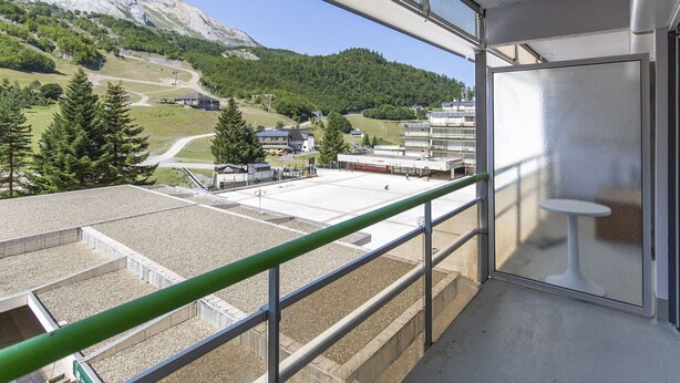 A balcony with a view of a mountainous landscape, a ski lift, and a building with multiple floors. - Lovely studio for 6 people at the foot of the slopes (Gourette)