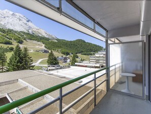 A balcony with a view of a mountainous landscape, a ski lift, and a building with multiple floors. - Lovely studio for 6 people at the foot of the slopes (Gourette)