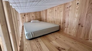 Un llit individual en una habitació amb parets i terres de fusta.