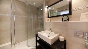 A modern bathroom with a glass-enclosed shower, a white sink, and a large mirror. - Renovated 1 bedroom flat for 2 persons (PORT GRIMAUD)