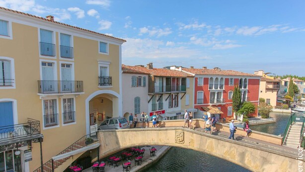 A canal-side building with outdoor seating and a bridge. - Renovated 1 bedroom flat for 2 persons (PORT GRIMAUD)