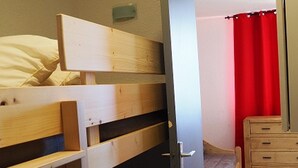 A room with a bunk bed, a wooden dresser, and a red curtain. - Renovated studio near slopes with balcony (Les Menuires)