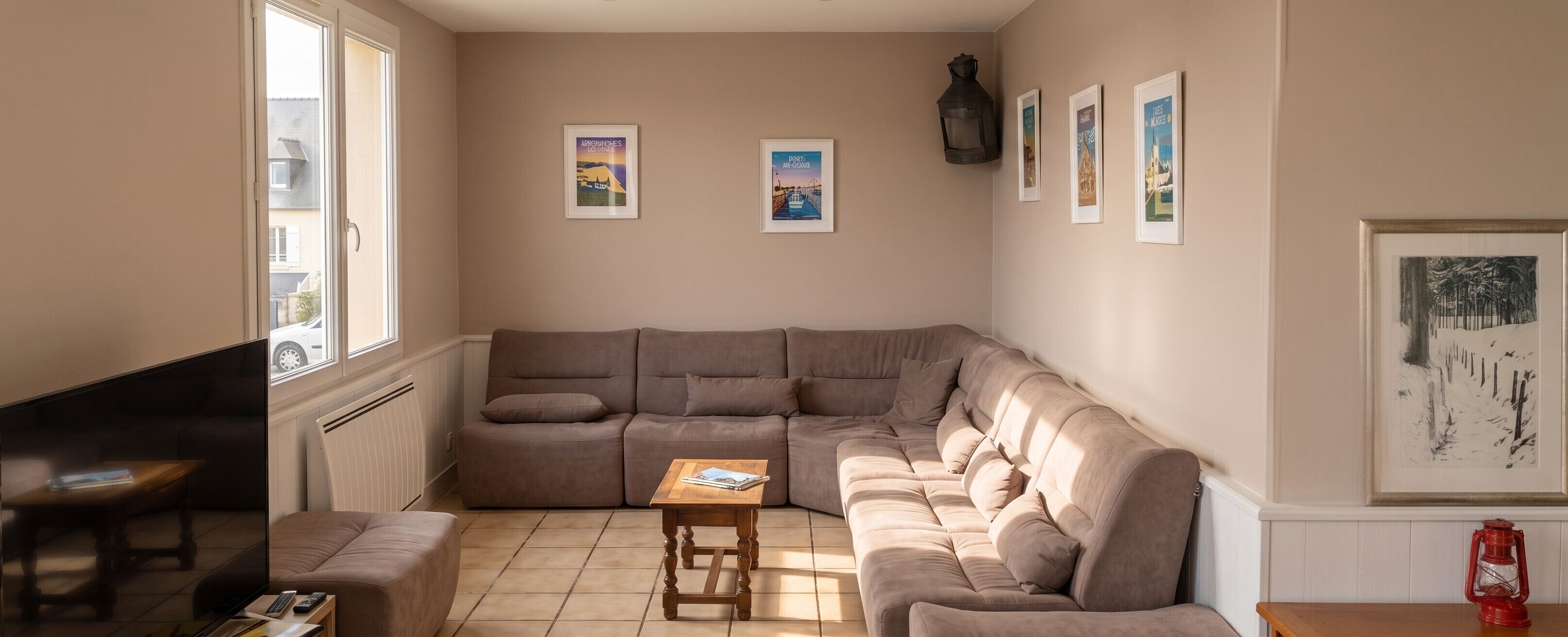 Ein Wohnzimmer mit einem großen, winkelförmigen Sofa, einem Holztisch, einem Fernseher und einem Kamin.