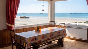 A dining area with a table, chairs, a bench, a bottle, and a glass. - Homerez - House in Arromanches-les-Bains (Arromanches-les-Bains)