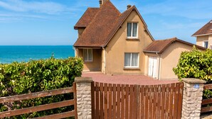 A two-story house with a red-tiled roof, a stone wall, and a wooden gate. - Homerez - House in Arromanches-les-Bains (Arromanches-les-Bains)