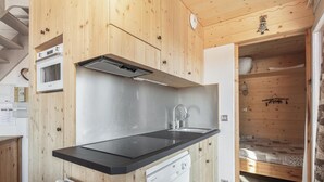 Una cocina compacta con armarios de madera, una encimera negra, horno empotrado y lavavajillas.