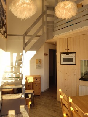 A modern kitchen with wooden cabinets, a built-in oven, and a dining area with a wooden table and chairs.