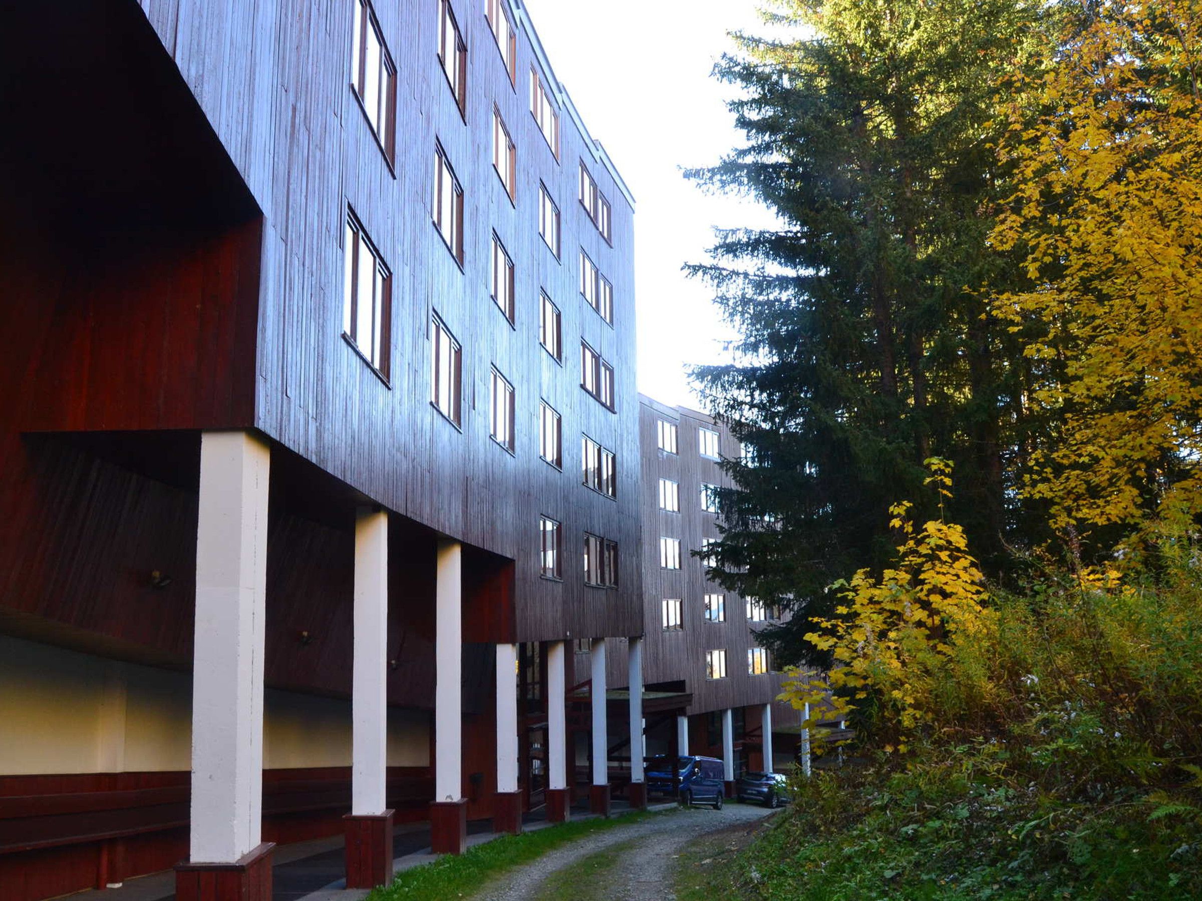 Ein mehrstöckiges Gebäude mit moderner Architektur, das eine Reihe von Fenstern und einen überdachten Gang zeigt.