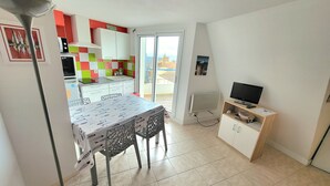 A compact living space with a dining area, kitchenette, and a television.