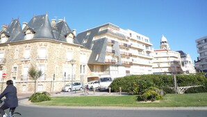 A historic stone building with a turret and a modern apartment complex in the background.