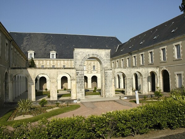 A courtyard with a central archway, surrounded by buildings with stone facades and multiple arches.