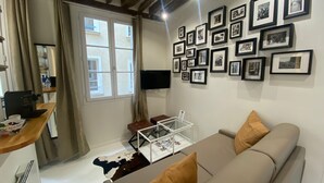 Un salon avec un canapé, une table basse et un mur recouvert de photographies encadrées.