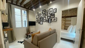 Une chambre moderne avec un canapé, un lit, une télévision et un mur recouvert de photos encadrées.