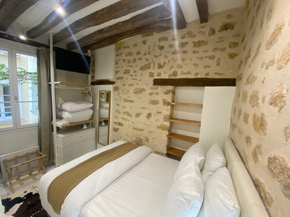 A bedroom with a bed, a wardrobe, a mirror, and a window.