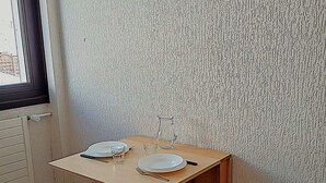 A small, tidy room with a wooden table set for two, a window, and a radiator. - Cozy studio for 2 in Tignes, pets allowed, at the foot of slopes (Tignes)