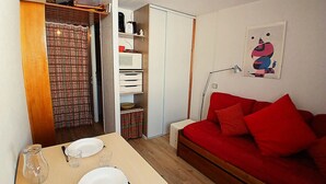 A compact living space with a kitchenette, a dining area with a table set for two, and a red sofa. - Cozy studio for 2 in Tignes, pets allowed, at the foot of slopes (Tignes)