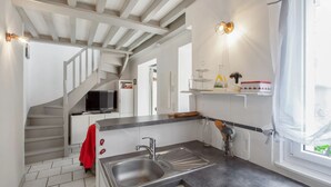 A modern kitchen with a built-in stove, a sink, and a staircase leading to another level. - Homerez - Charming House near Sainte Catherine (Honfleur)