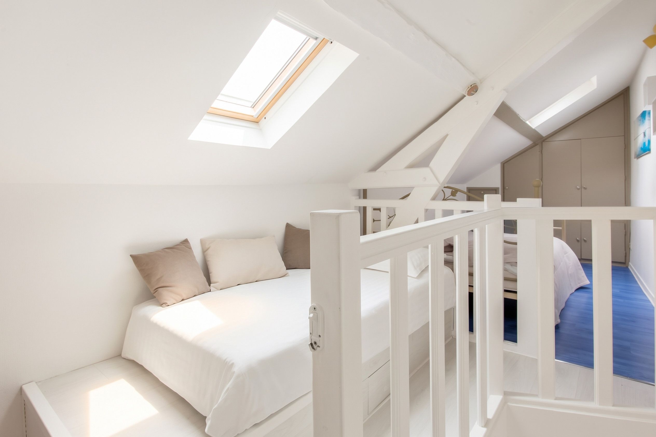 A bedroom with a sloped ceiling, a skylight, a bunk bed, and a wardrobe.