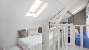 A bedroom with a bunk bed, a skylight, a white wardrobe, and a staircase. - Homerez - Charming House near Sainte Catherine (Honfleur)