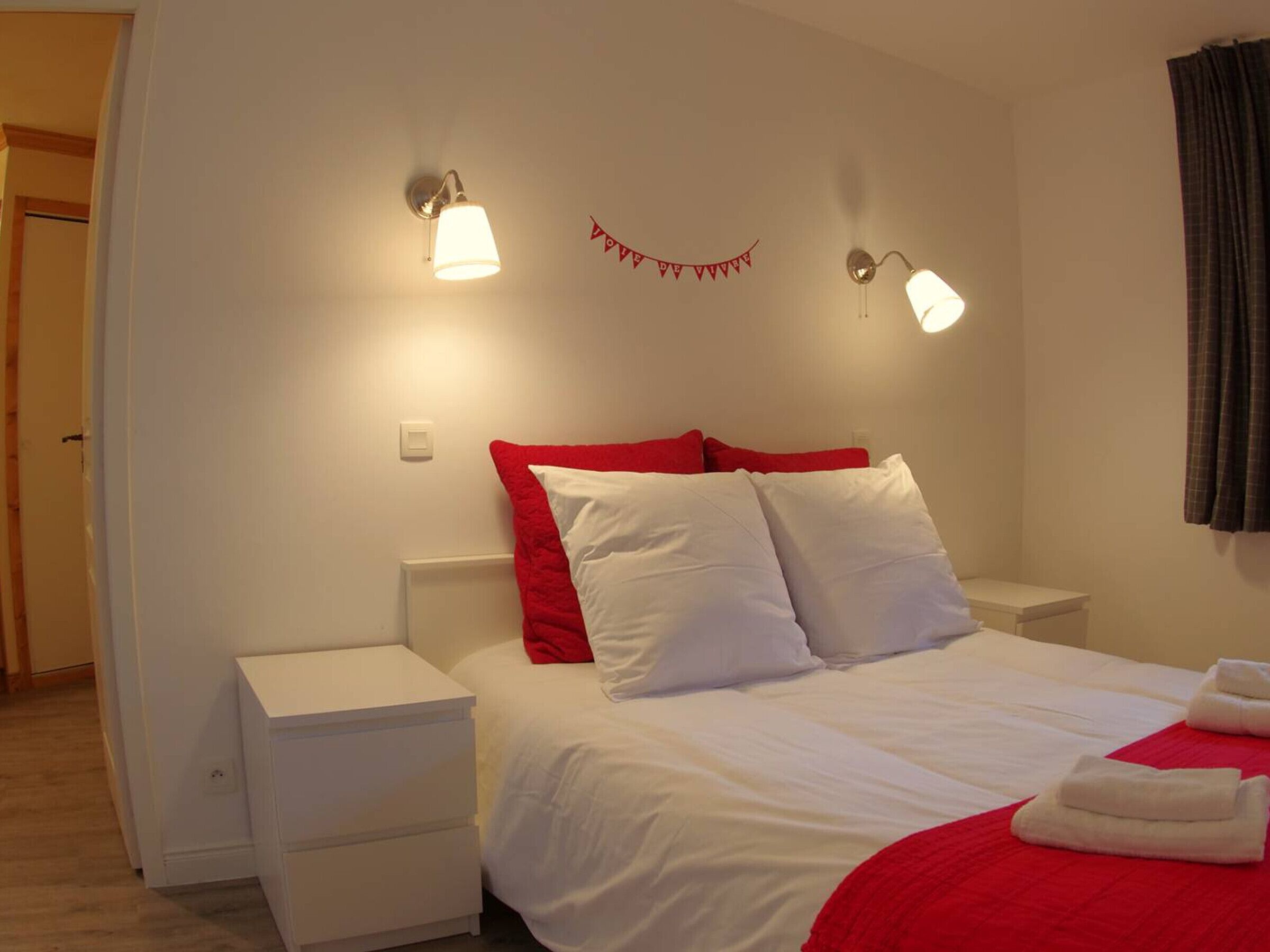 Een hotelkamer met een bed, twee nachtkastjes en twee wandlampen.