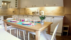 A modern kitchen with white cabinets, a wooden dining table set with plates and glasses, and a coffee maker on the counter. - "Spacious 3-Room Apartment, Ski-In/Ski-Out, Sleeps 7, Forest Hamlet, Les Avanchers-Valmorel" (Valmorel)