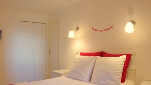 A neatly made bed with white and red bedding, two bedside lamps, and a red wall decoration. - "Spacious 3-Room Apartment, Ski-In/Ski-Out, Sleeps 7, Forest Hamlet, Les Avanchers-Valmorel" (Valmorel)
