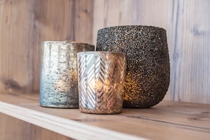 Trois photophores décoratifs sont posés sur une étagère en bois.