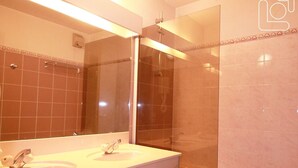 A bathroom with two sinks, a mirror, and a glass-enclosed shower.